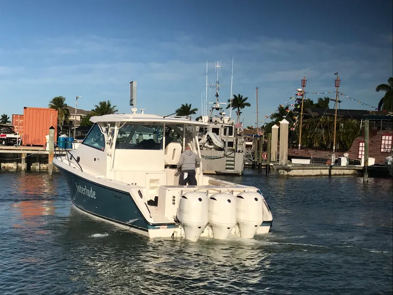 Slide: The Image of 2016 Pursuit OS 385 Offshore boat in marina, sunny day, palm trees in background. - 3