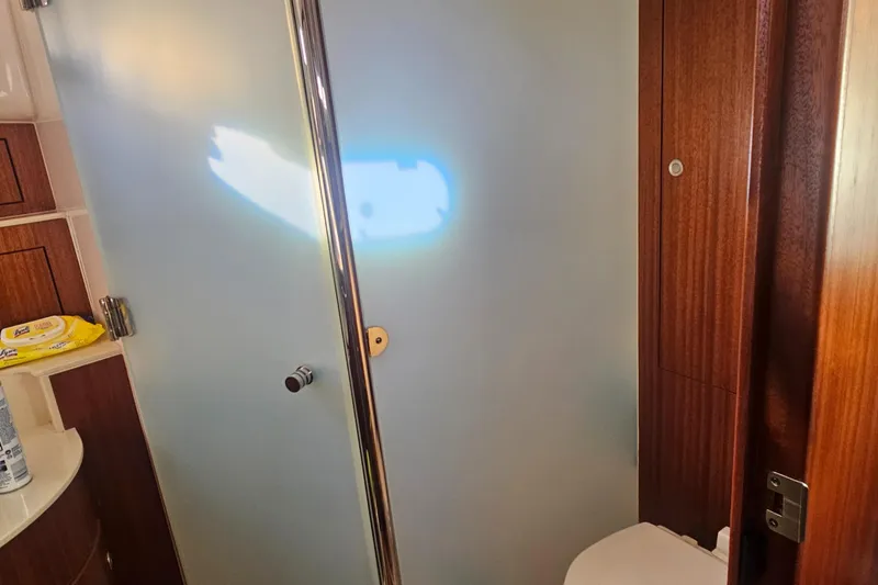 Slide: The Image of Bathroom interior of 2016 Pursuit OS 385 Offshore boat, featuring wooden accents and modern fixtures. - 7