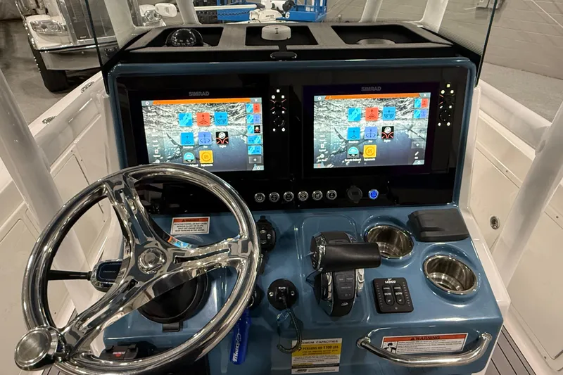 Slide: The Image of 2022 Crevalle 26 HCO boat dashboard with dual Simrad displays and chrome steering wheel. - 6