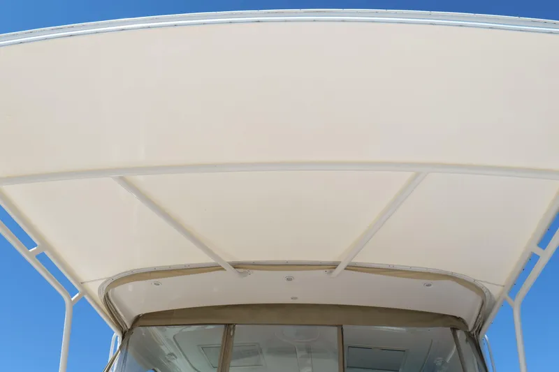Slide: The Image of 2008 Tiara Yachts 4300 Sovran cockpit with cushioned seating and wooden table by the water. - 16