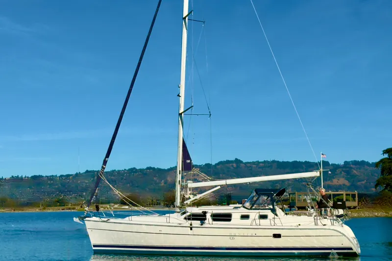 Slide: The Image of 2003 Hunter 426 Deck Salon sailboat on calm water with scenic background. - 2