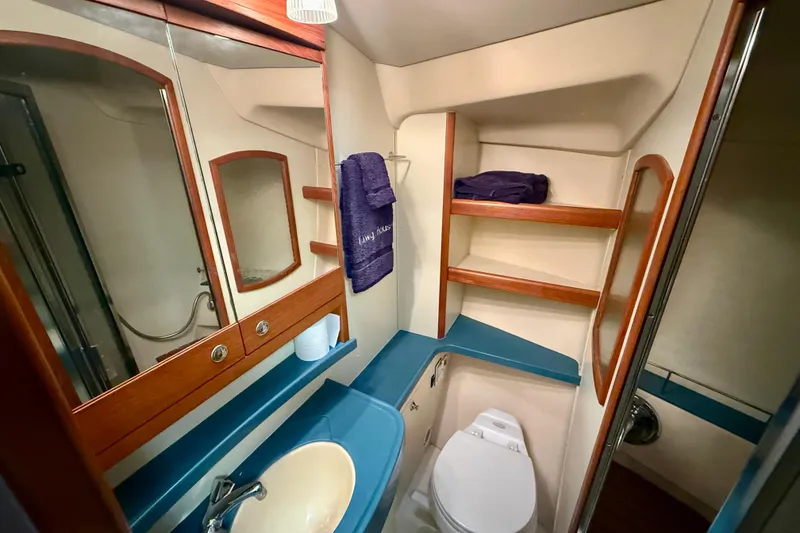 Slide: The Image of 2003 Hunter 426 Deck Salon bathroom with sink, toilet, mirror, and wooden shelves. - 22