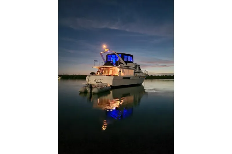 The Image of 1987 Bayliner 4550 Motoryacht illuminated at dusk on calm water. - 0