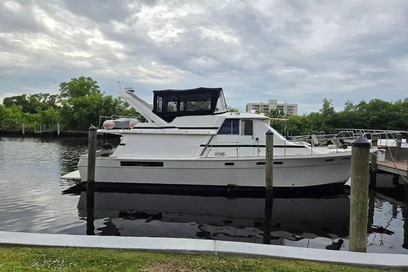 Slide: The Image of 1987 Bayliner 4550 Motoryacht docked on a calm waterway under a cloudy sky. - 1