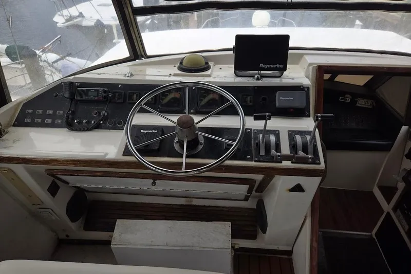 Slide: The Image of 1987 Bayliner 4550 Motoryacht helm with steering wheel and navigation controls. - 12