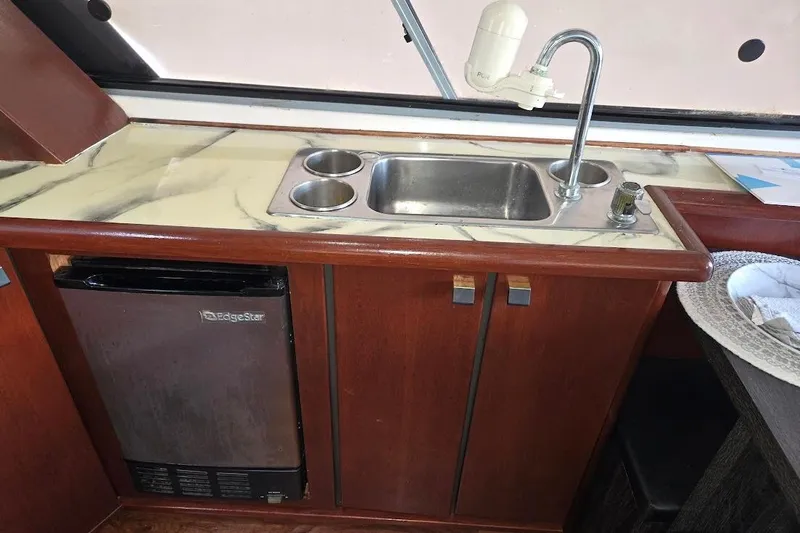 Slide: The Image of 1987 Bayliner 4550 Motoryacht kitchen with sink, marble countertop, and mini fridge. - 23