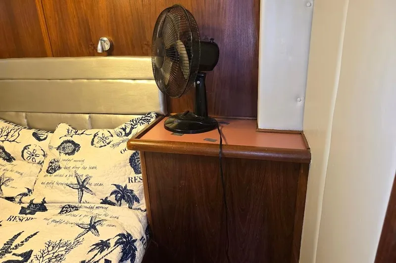 Slide: The Image of 1987 Bayliner 4550 Motoryacht cabin with nautical-themed bedding and a fan. - 37