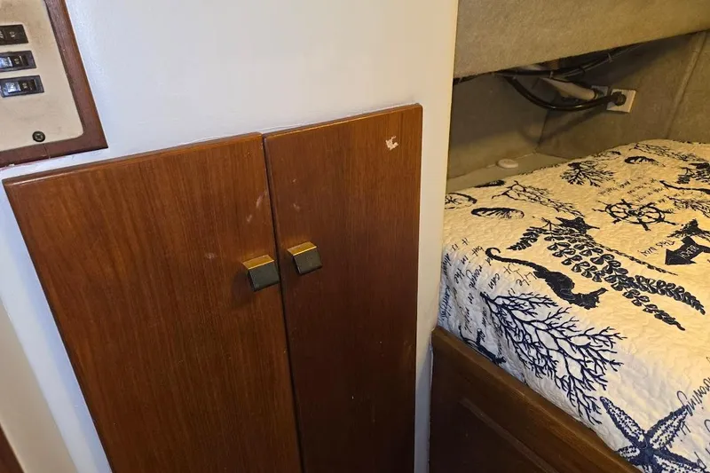 Slide: The Image of 1987 Bayliner 4550 Motoryacht interior with wooden cabinet and nautical-themed bedding. - 38