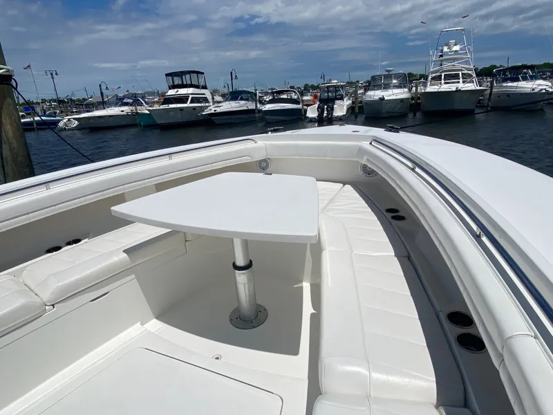 Slide: The Image of 2016 Regulator 41 boat with seating and table, docked at a marina under a cloudy sky. - 18