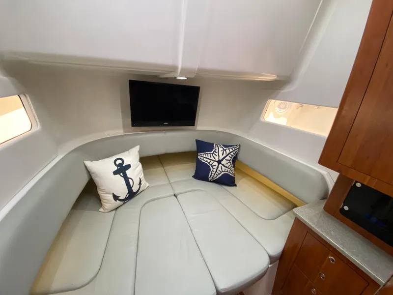 Slide: The Image of 2016 Regulator 41 boat interior with cozy seating, nautical pillows, and a mounted TV. - 2