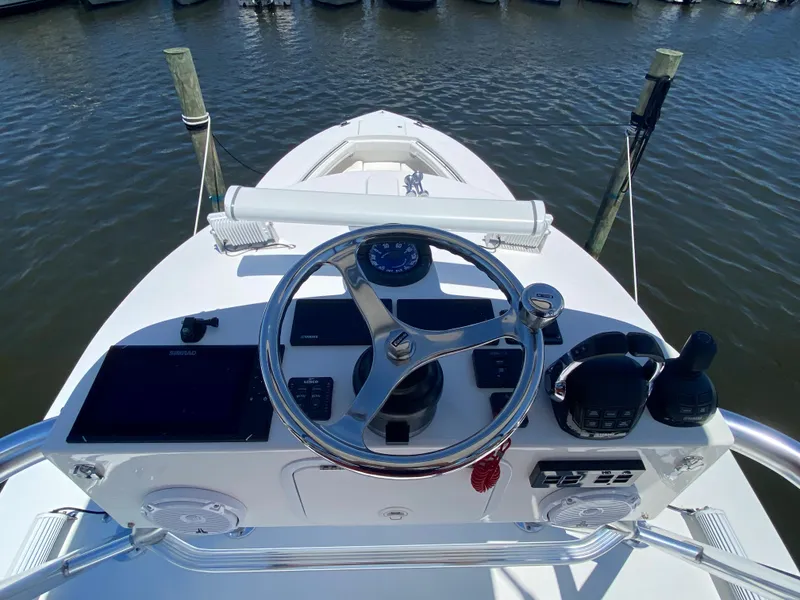 Slide: The Image of 2016 Regulator 41 boat helm with steering wheel and controls, docked on calm water. - 22