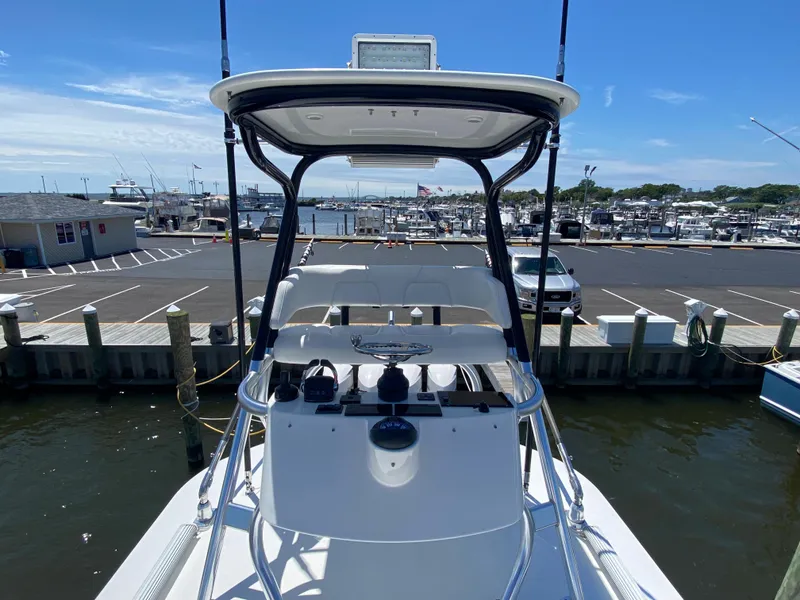 Slide: The Image of 2016 Regulator 41 boat docked at marina, featuring helm station and T-top under clear blue sky. - 25