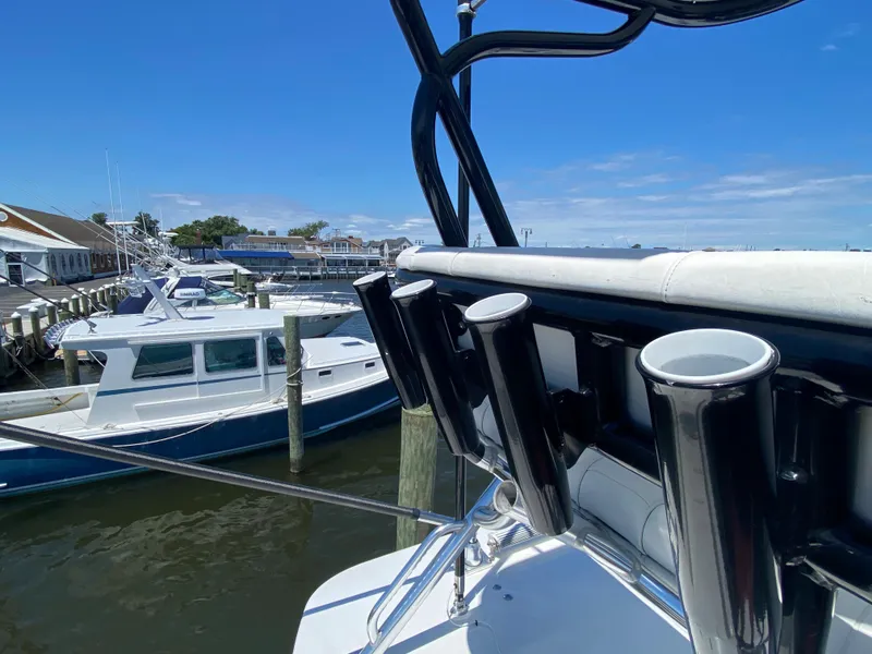 Slide: The Image of 2016 Regulator 41 boat docked, featuring rod holders and marina view under clear blue sky. - 28