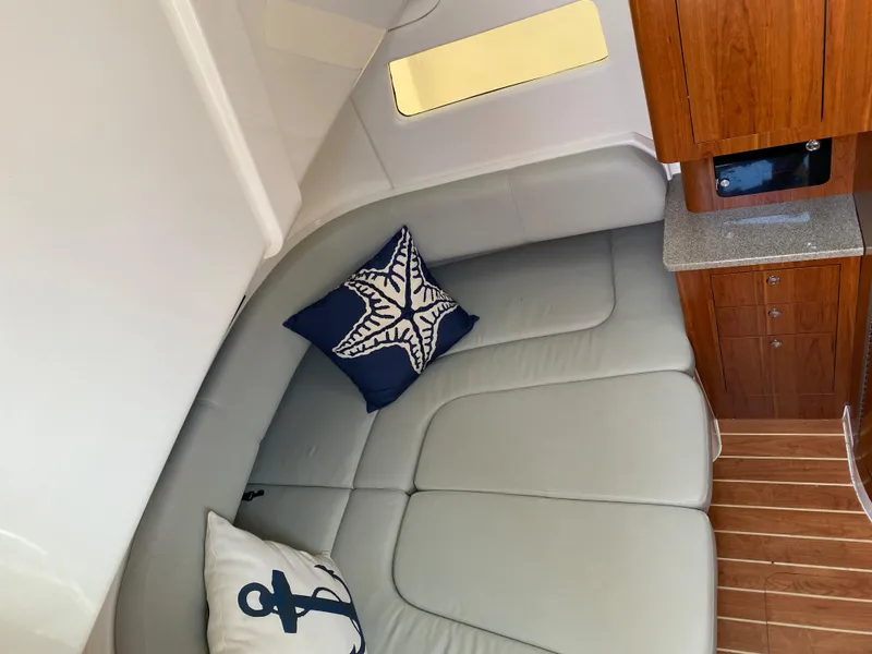 Slide: The Image of 2016 Regulator 41 interior with cushioned seating, nautical-themed pillows, and wooden cabinetry. - 46