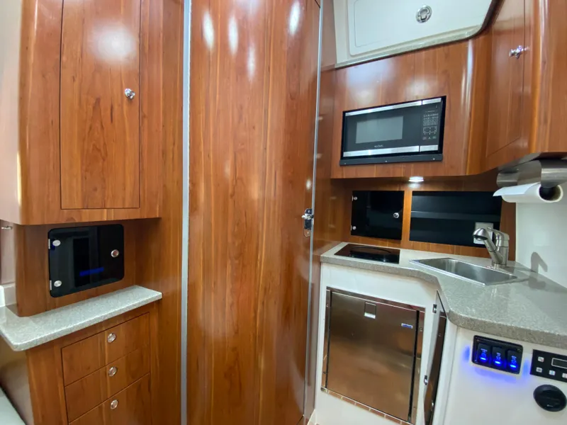 Slide: The Image of 2016 Regulator 41 boat interior with wood cabinetry, microwave, sink, and modern appliances. - 47