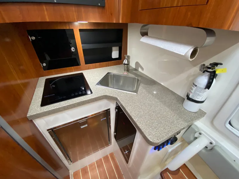 Slide: The Image of Compact kitchen area in a 2016 Regulator 41 boat with sink, stove, and storage. - 48