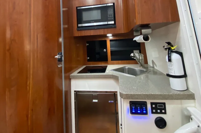 Slide: The Image of 2016 Regulator 41 boat interior kitchen with microwave, sink, and fire extinguisher. - 50