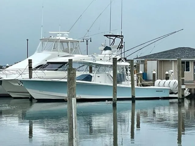 Slide: The Image of 2016 Regulator 41 boat docked at marina, calm water reflection, fishing rods visible. - 8