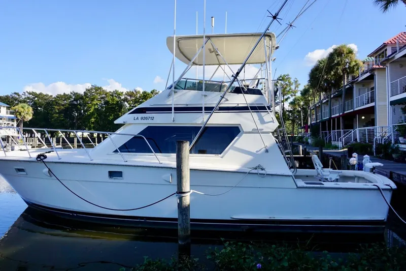 The Image of 1986 Hatteras 41 Convertible yacht docked by waterfront homes. - 0