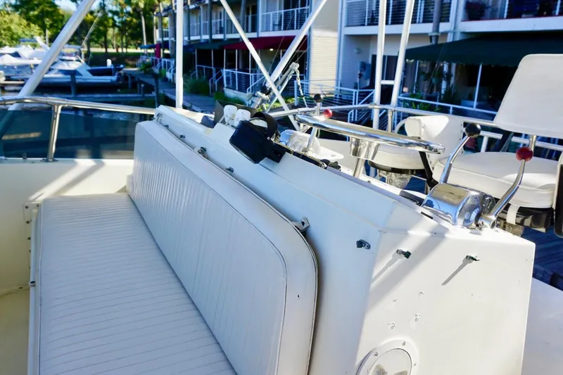 Slide: The Image of 1986 Hatteras 41 Convertible yacht helm with seating and controls, docked near waterfront buildings. - 16