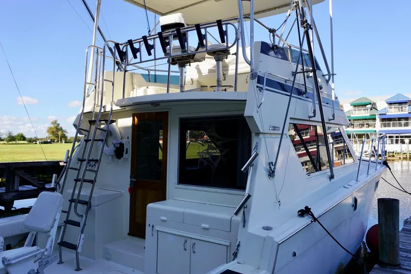 Slide: The Image of 1986 Hatteras 41 Convertible yacht docked, featuring a spacious deck and ladder access. - 19