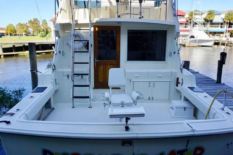 Slide: The Image of 1986 Hatteras 41 Convertible yacht docked, featuring spacious deck and fishing chair. - 22