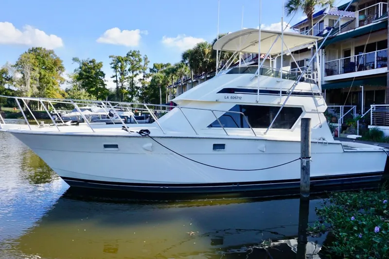 Slide: The Image of 1986 Hatteras 41 Convertible yacht docked by waterfront homes. - 3