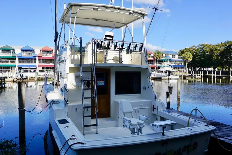 Slide: The Image of 1986 Hatteras 41 Convertible yacht docked at marina with colorful buildings in background. - 8