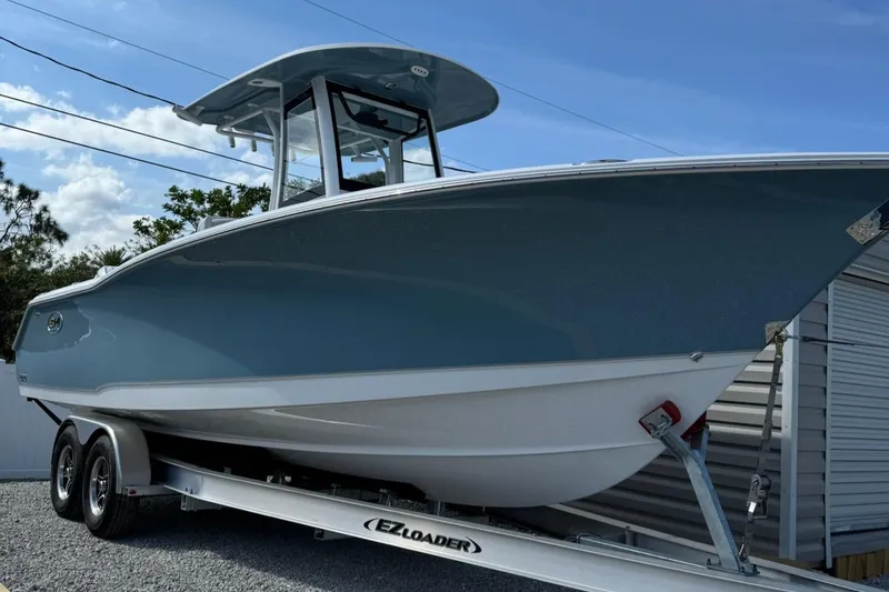 The Image of 2025 Sea Hunt Gamefish 27 Coffin Box boat on trailer, side view under blue sky. - 0
