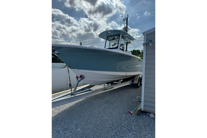 Slide: The Image of 2025 Sea Hunt Gamefish 27 Coffin Box boat on trailer, parked outdoors under cloudy sky. - 11