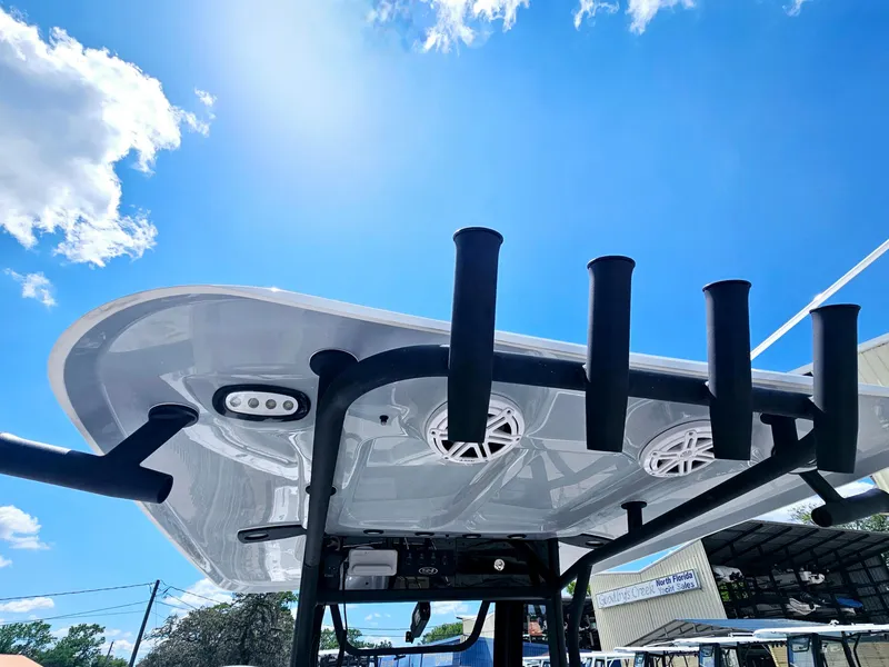 Slide: The Image of 2025 Sea Hunt Ultra 245 SE boat with T-top and rod holders under a clear blue sky. - 21