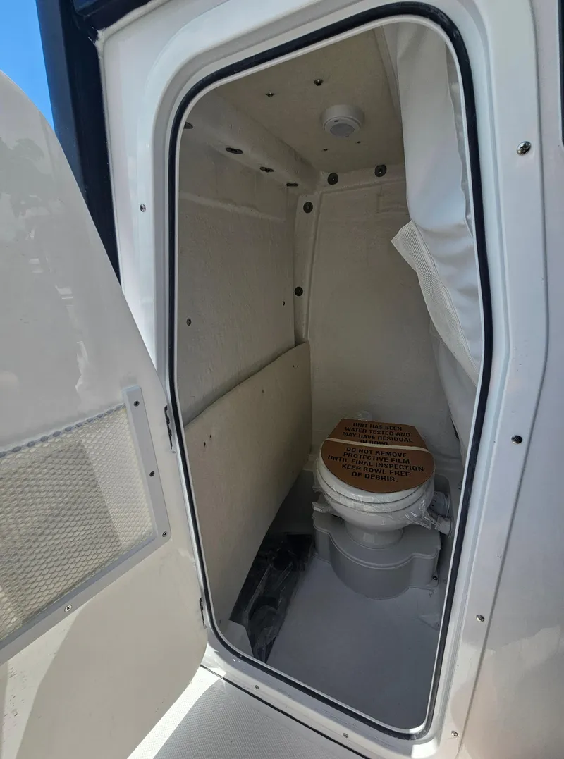 Slide: The Image of 2025 Sea Hunt Ultra 245 SE boat interior with compact marine toilet. - 23