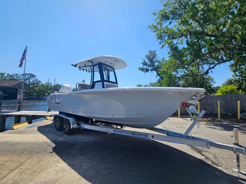 Slide: The Image of 2025 Sea Hunt Ultra 245 SE boat on trailer, parked near water, sunny day. - 6