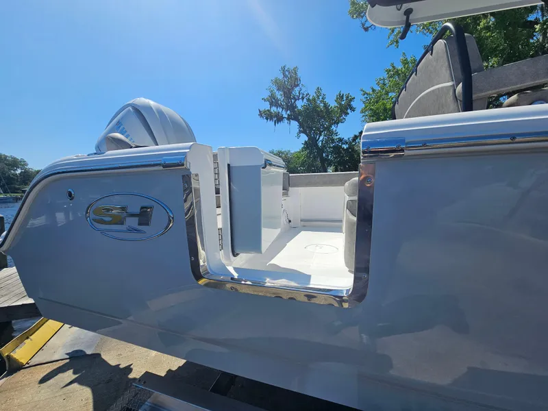 Slide: The Image of 2025 Sea Hunt Ultra 245 SE boat with open side door, docked under clear blue sky. - 7