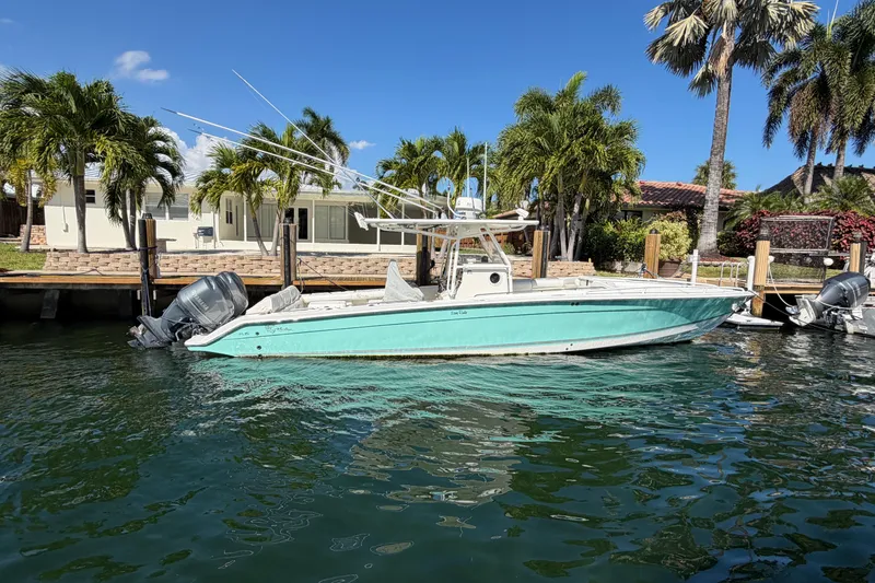 The Image of 2004 Marlago 35fs boat docked by palm trees and waterfront home. - 0