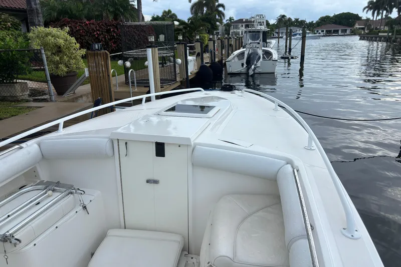 Slide: The Image of 2004 Marlago 35fs boat docked by a waterfront home with lush greenery. - 10