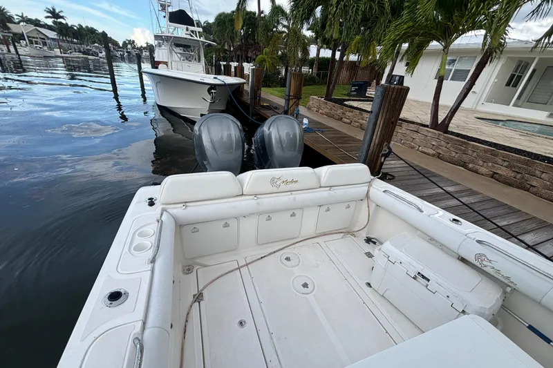 Slide: The Image of 2004 Marlago 35fs boat docked by a waterfront, featuring dual outboard motors. - 5