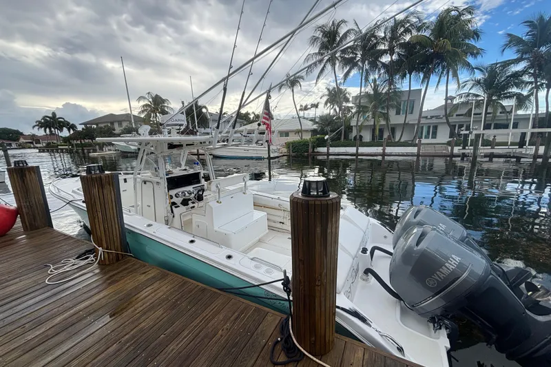 Slide: The Image of 2004 Marlago 35fs boat docked by palm trees, featuring Yamaha engines. - 7