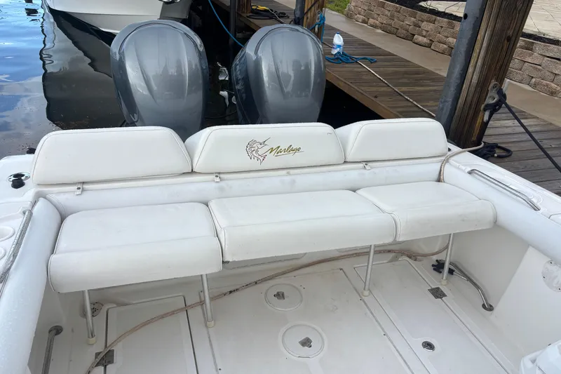 Slide: The Image of 2004 Marlago 35fs boat with white seating and dual outboard motors at dock. - 8