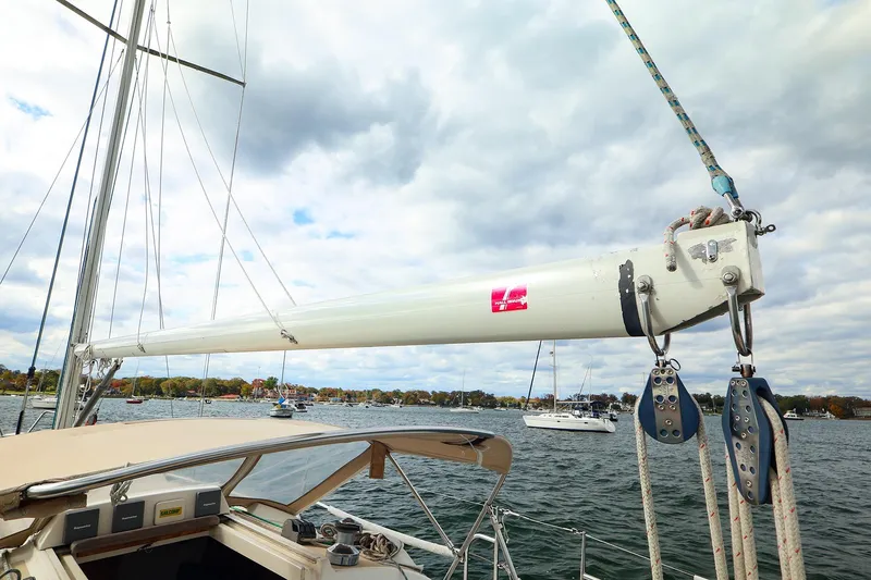 Slide: The Image of 1999 J Boats J/32 sailboat mast and boom on a cloudy day, anchored in a scenic harbor. - 13