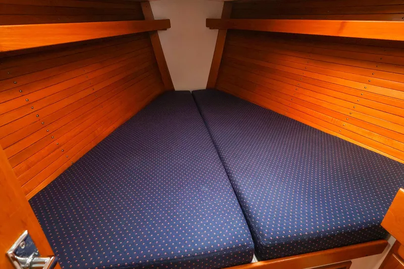 Slide: The Image of 1999 J Boats J/32 cabin interior with blue cushioned berth and wooden paneling. - 28