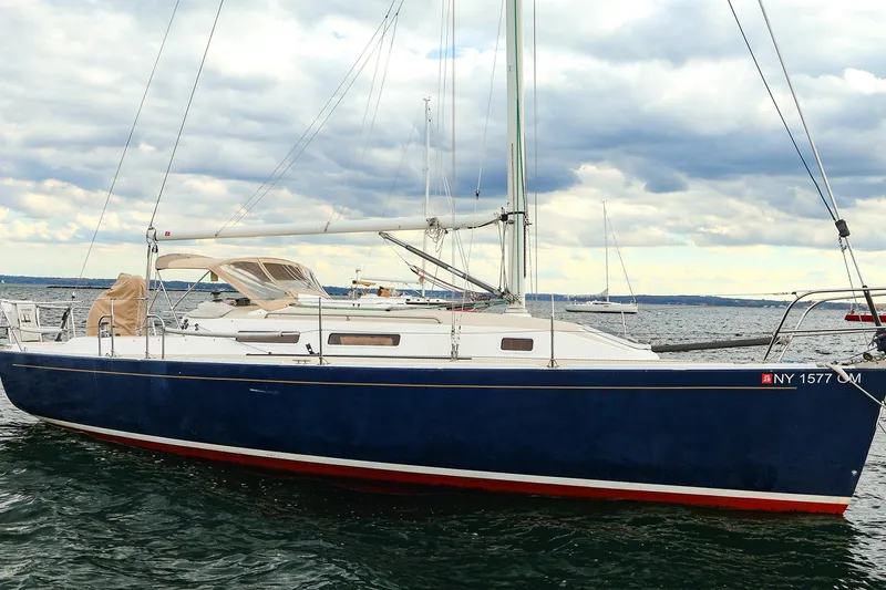 Slide: The Image of 1999 J Boats J/32 sailboat with blue hull on calm water under cloudy sky. - 31