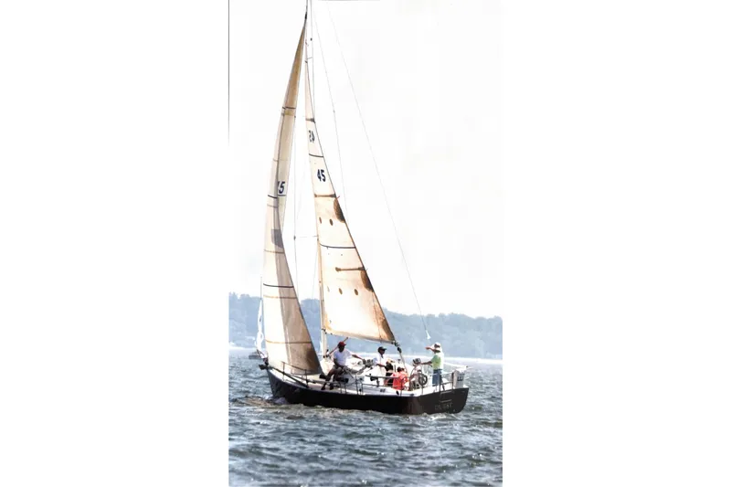 Slide: The Image of Sailing on a 1999 J Boats J/32 with crew, open water, and distant shoreline. - 32
