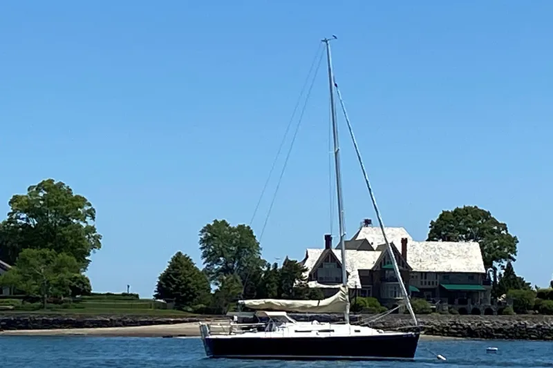 Slide: The Image of 1999 J Boats J/32 sailboat anchored near a coastal mansion with trees. - 4