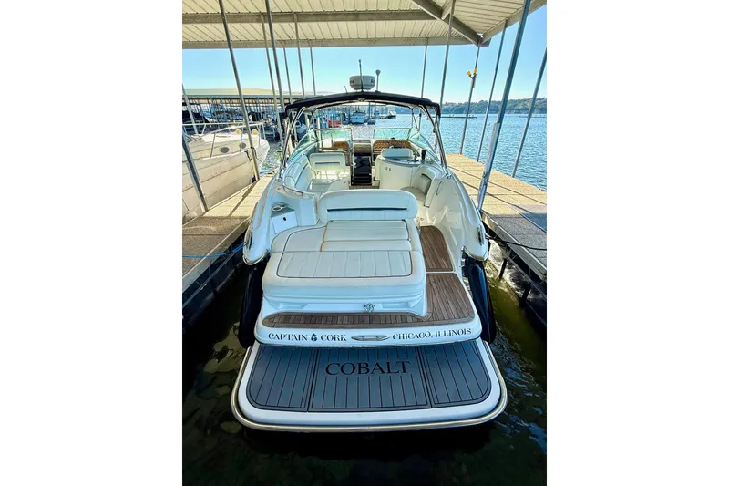 Slide: The Image of 2007 Cobalt 323 boat docked, rear view, with white seating and wooden deck. - 15