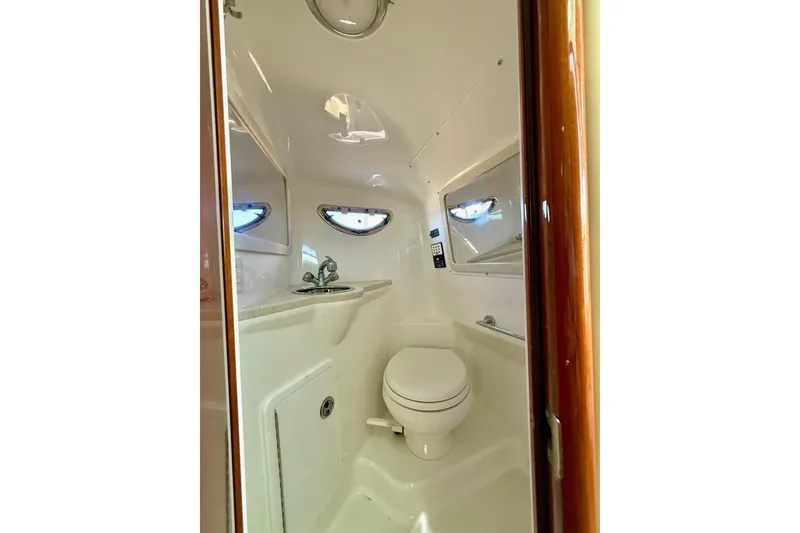 Slide: The Image of 2007 Cobalt 323 boat interior bathroom with toilet, sink, and porthole windows. - 31
