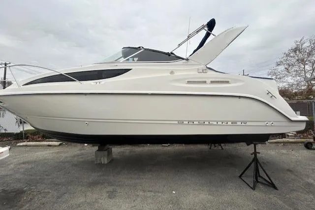 The Image of 2003 Bayliner 285 boat on stands, side view, outdoors, overcast sky. - 0