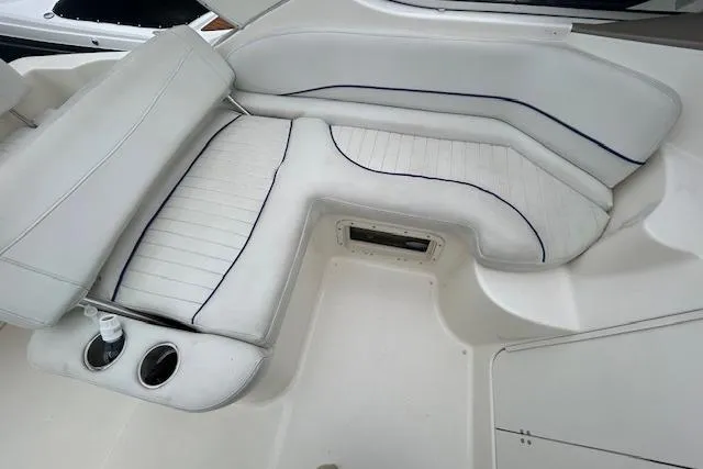Slide: The Image of 2003 Bayliner 285 boat interior with white cushioned seating and cup holders. - 10
