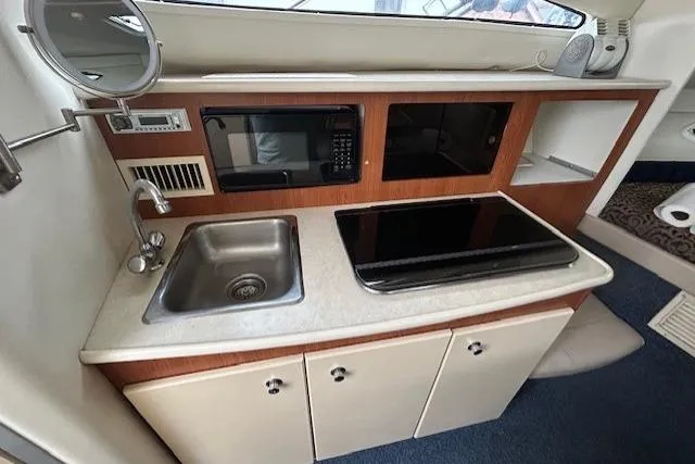 Slide: The Image of 2003 Bayliner 285 boat kitchen with sink, stove, and microwave. - 18
