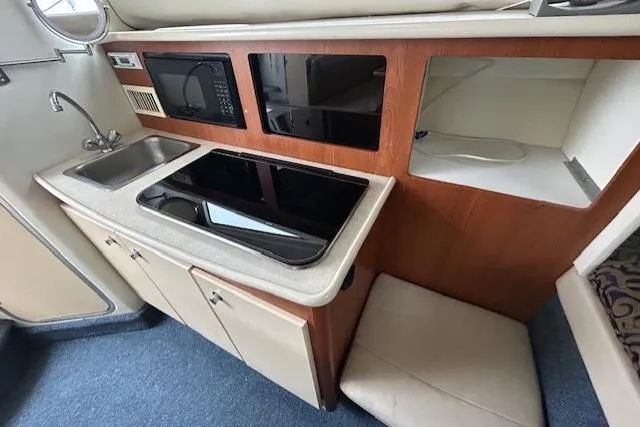 Slide: The Image of 2003 Bayliner 285 boat kitchen with sink, microwave, and stove. - 19
